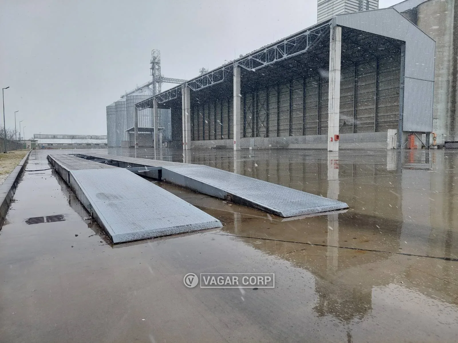 Čelične rampe i most kamionske vage na mokrom betonskom platou